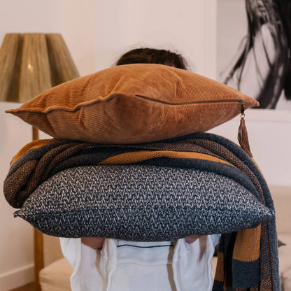 Person holding a stack of pillows and blankets with a blurred background