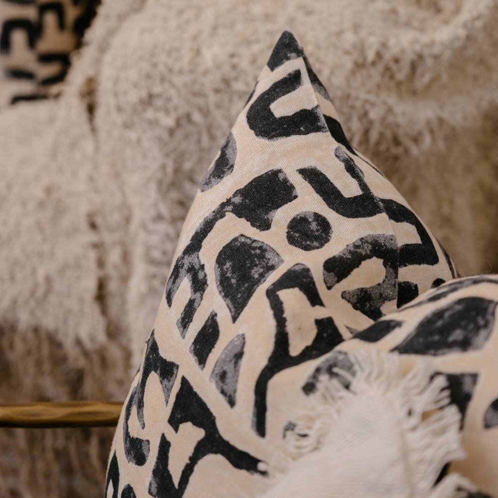 Decorative pillow with black geometric pattern on beige background