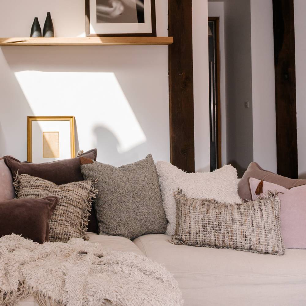 Decorative pillows on a sofa with a neutral color palette in a room setting.