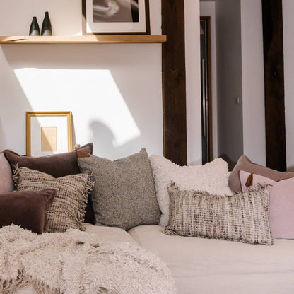 Decorative pillows on a sofa with a neutral color palette in a room setting.