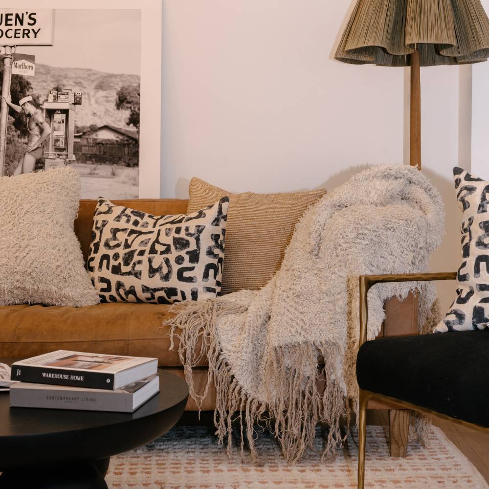 Living room with a beige sofa, patterned pillows, and a lamp.