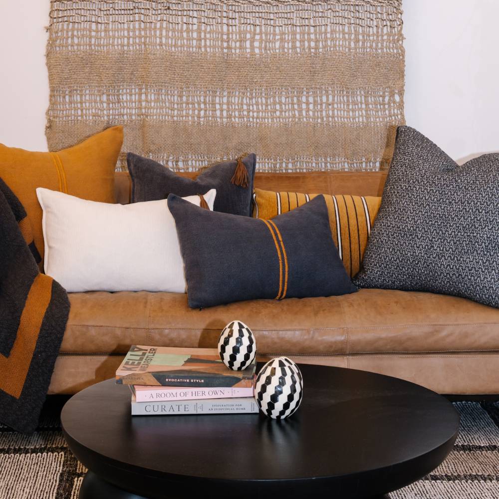 Decorative pillows on a brown sofa with a coffee table in the foreground