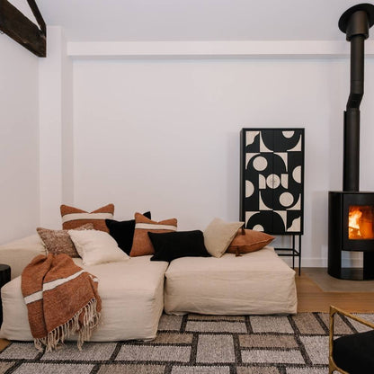 Cozy living room with a white sofa, patterned rug, and wooden stove.