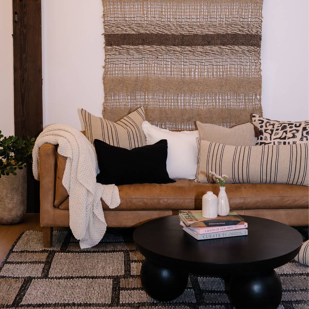 Living room with a brown sofa, decorative pillows, and a black coffee table.