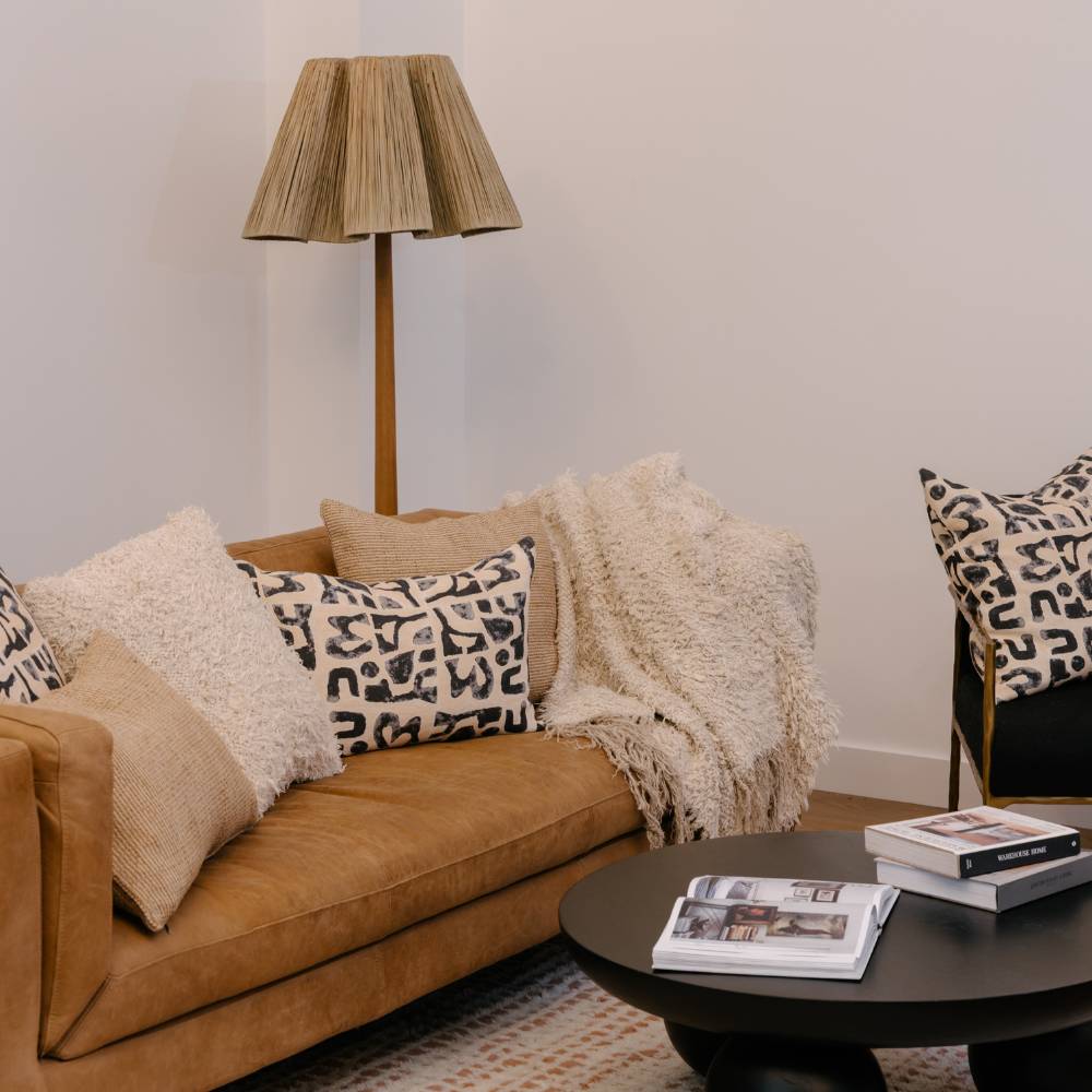 Cozy living room with brown sofa, patterned cushions, and a lamp.