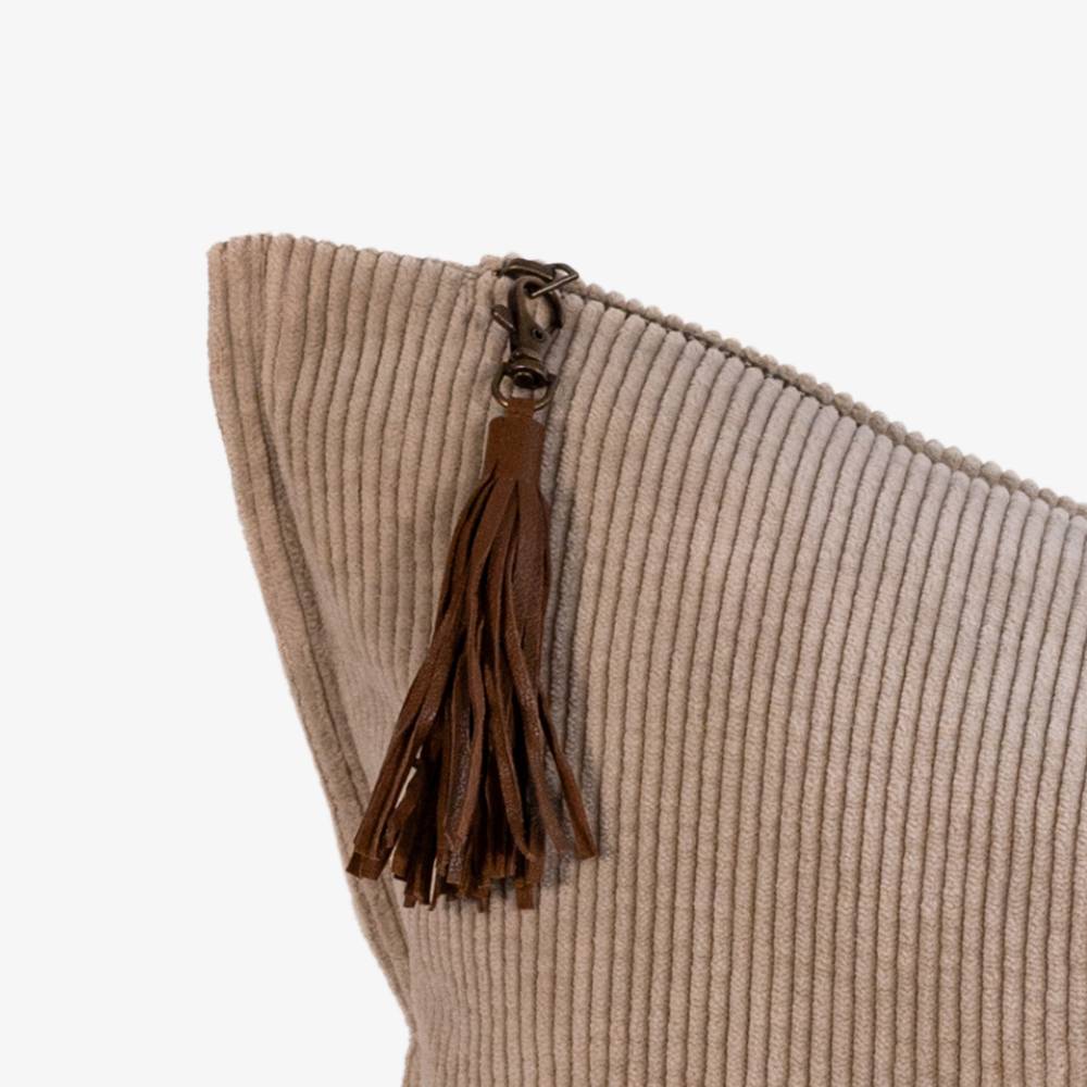 Beige pillow with a brown tassel on a white background