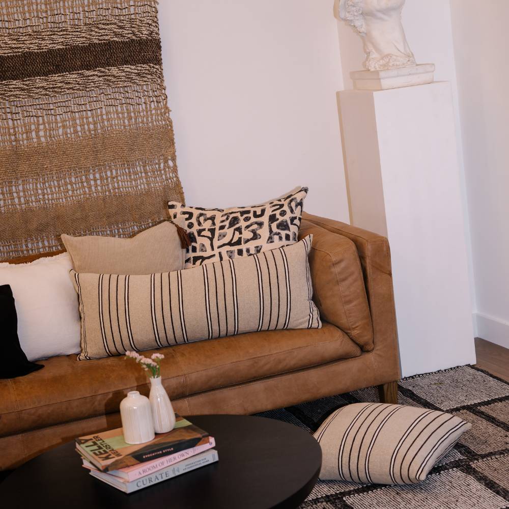 Brown leather sofa with patterned cushions in a living room setting.