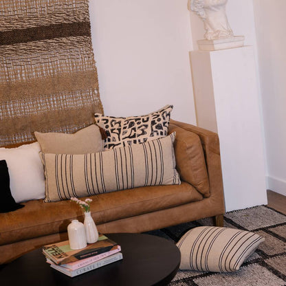 Brown leather sofa with patterned cushions in a living room setting.