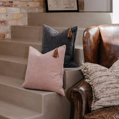 Decorative pillows on a staircase with a leather armchair in the foreground.