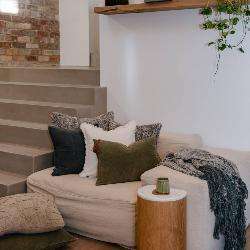 Beige sofa with decorative pillows and a plant in a modern living room.