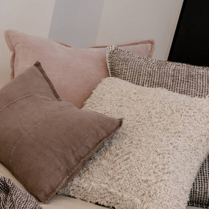 Close-up of textured pillows on a sofa with a neutral background