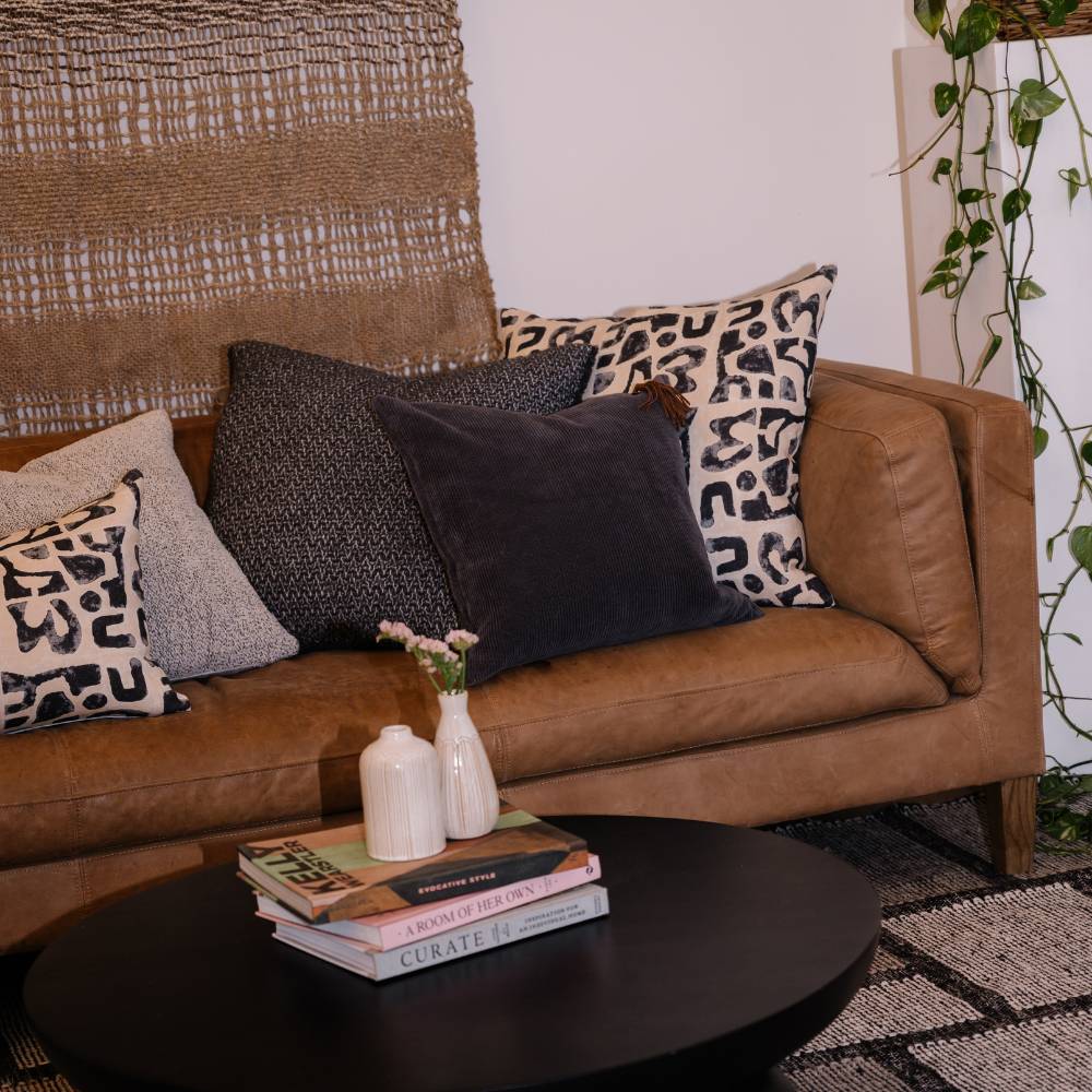 Brown leather sofa with patterned cushions in a living room setting.