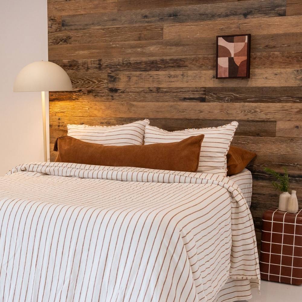Bedroom with wooden wall, striped bedding, and abstract art.