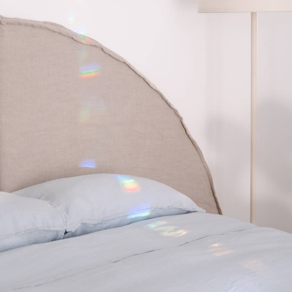 Close-up of a bed with a beige headboard and sky blue bedding.