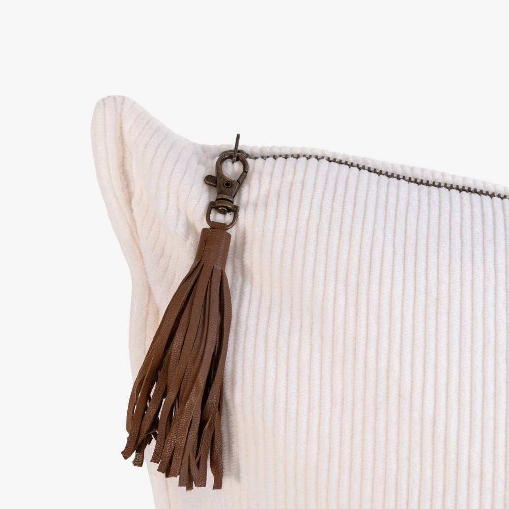 Close-up of a white textured pouch with a brown leather tassel on a light beige background
