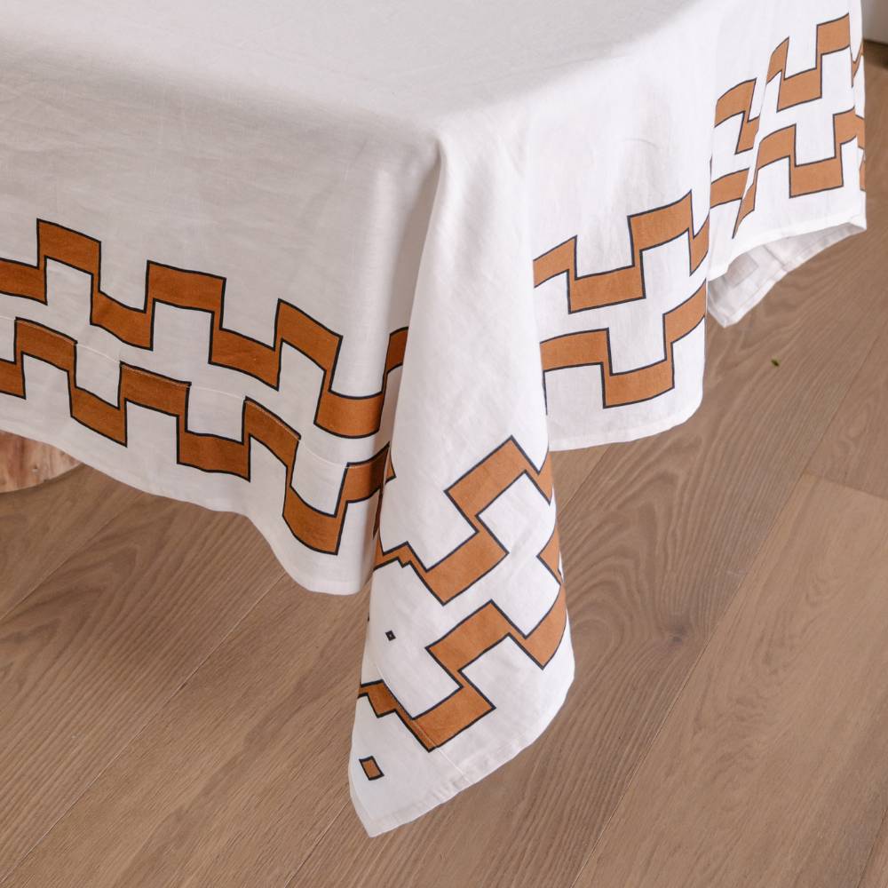 White tablecloth with brown geometric pattern on a wooden floor