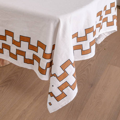 White tablecloth with brown geometric pattern on a wooden floor