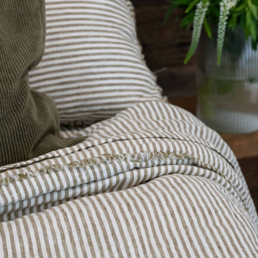 Close-up of striped fabric with a pillow and plant in the background