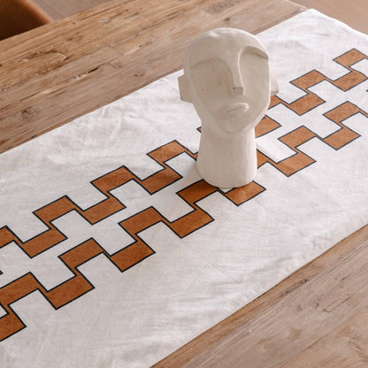 White ceramic display on a white runner with geometric nutmeg design on a wooden table