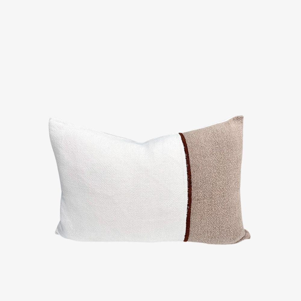 A rectangular decorative throw pillow with a split design, featuring a white textured fabric half and a taupe-beige textured fabric half divided by a thin dark brown vertical stripe.