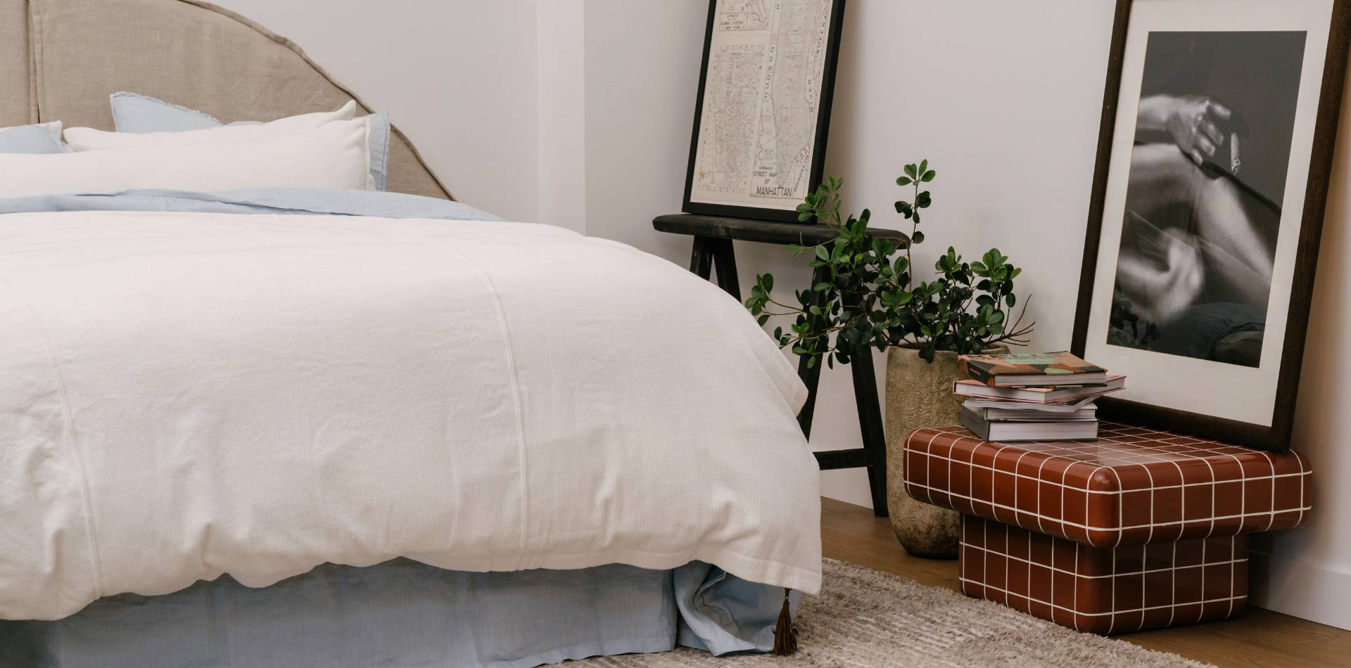 Neatly made bed with white bedding in a bedroom setting.