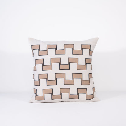 A pillow with a repeating geometric pattern of interlocking beige and white outlined in black on a white background