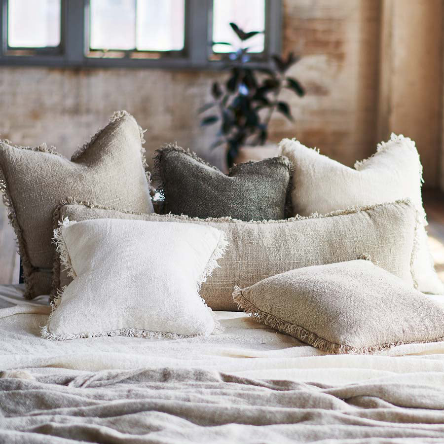 hand woven linen cushions with a boho fringing in neutral tones displayed for bedroom inspiration