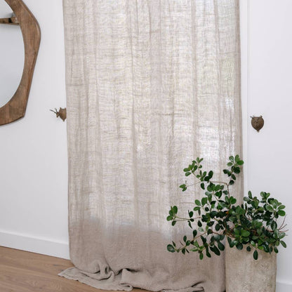 Close-up of a natural or beige curtain with a soft texture tied back with a fabric band on a white background