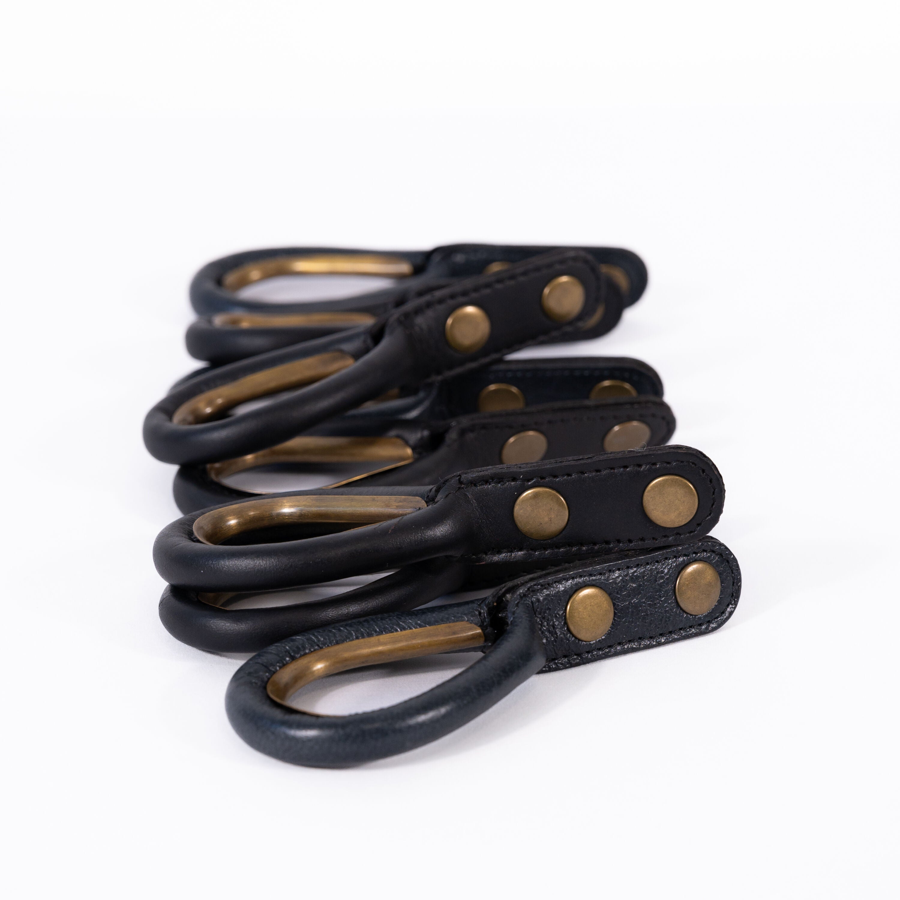 Set of black leather rings with antique brass-colored rings and rivets on a white background
