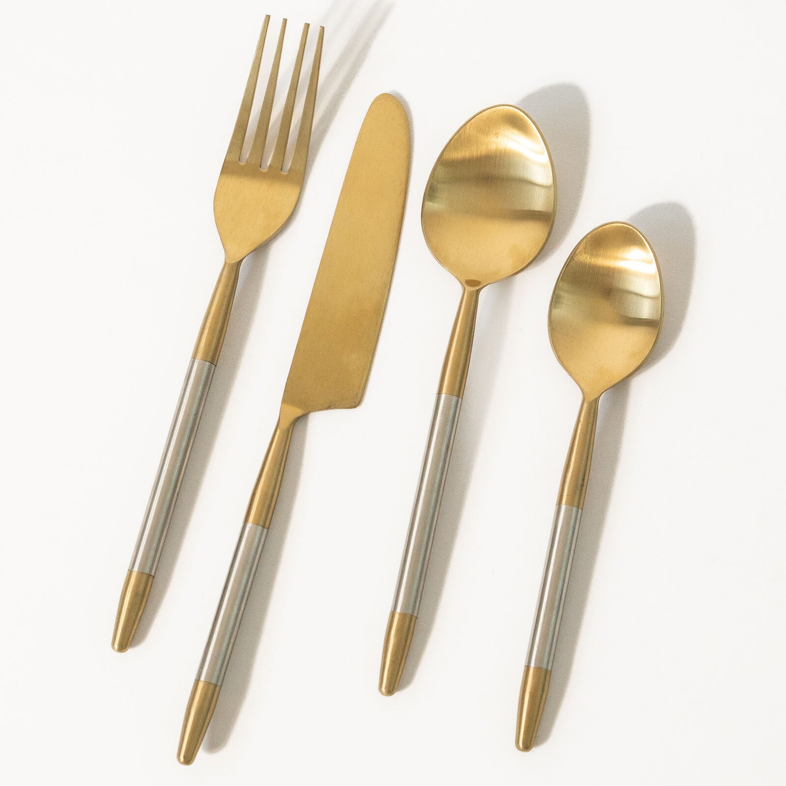 Set of gold and silver cutlery on a white background