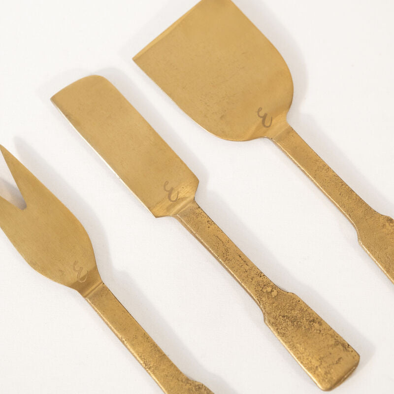Close-up look on a set of gold cheese tools set on a white background