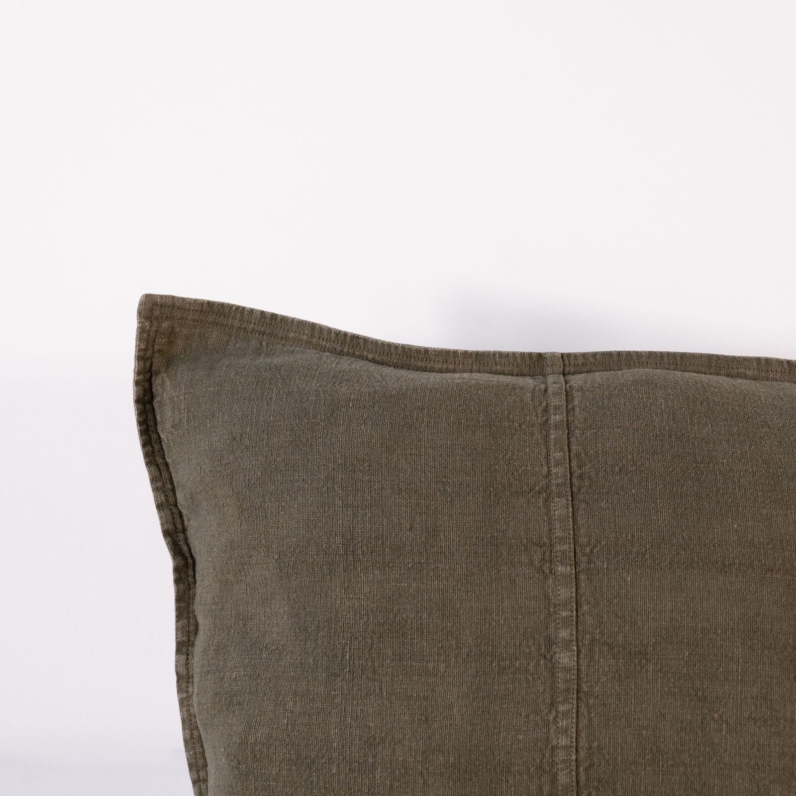 A close-up of a square, textured pillow in a deep, muted olive green color, with subtle vertical stitching details.