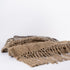 Folded handwoven natural jute rugs with fringe on a white background