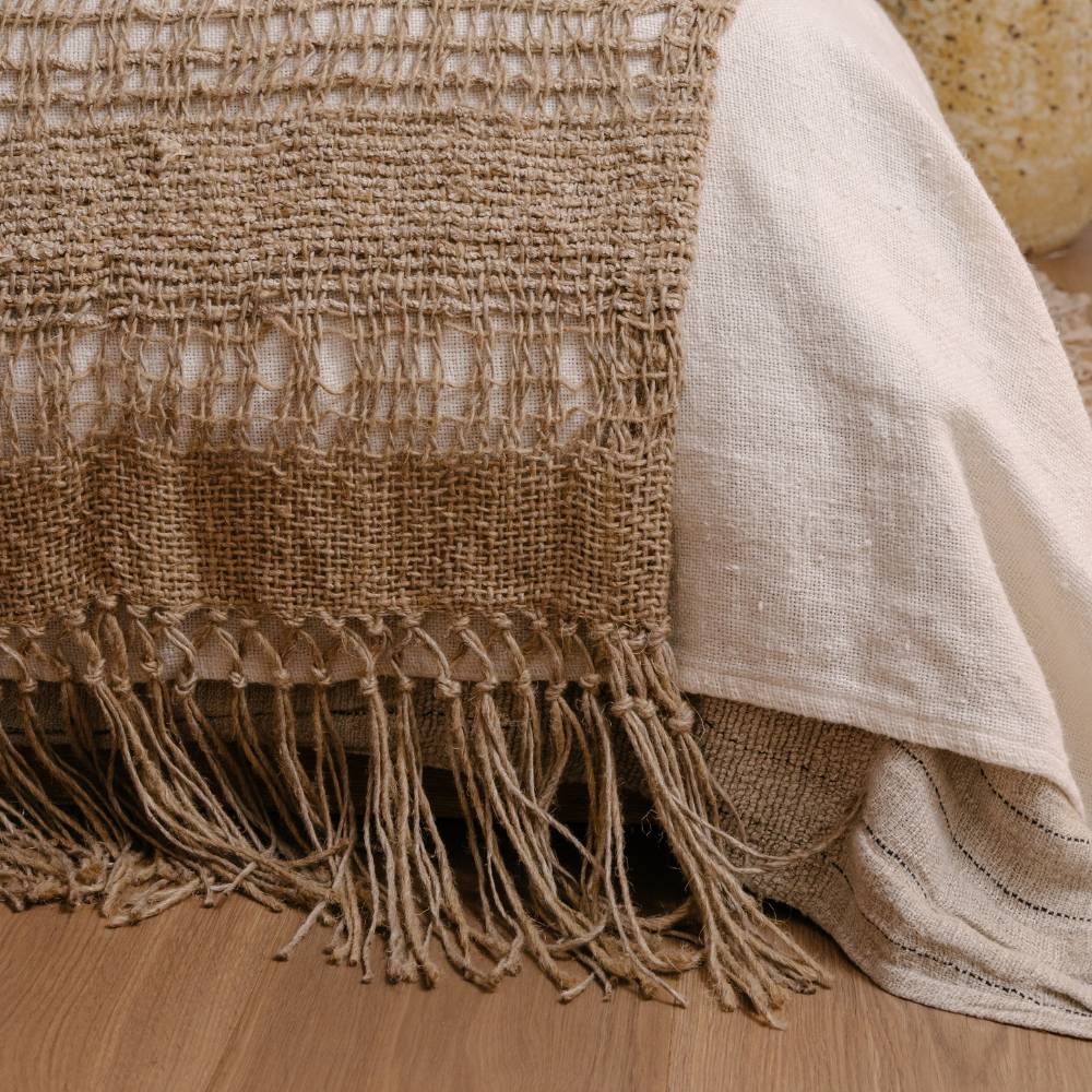 Textured beige blanket with fringes on a wooden surface