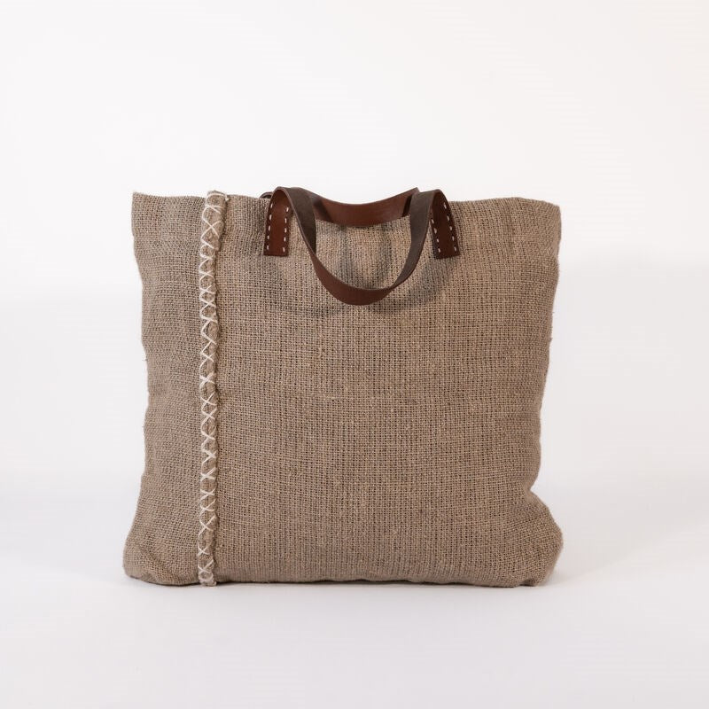 Natural jute fiber textured tote bag with leather handles on a white background