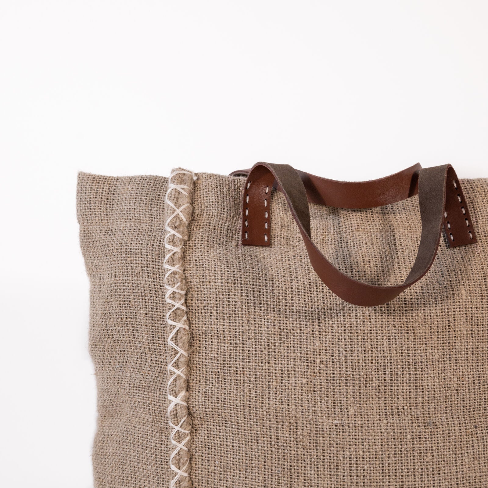 Natural jute fiber textured tote bag with leather handles on a white background