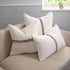 White pillows with brown stripes on a sofa against a neutral background.
