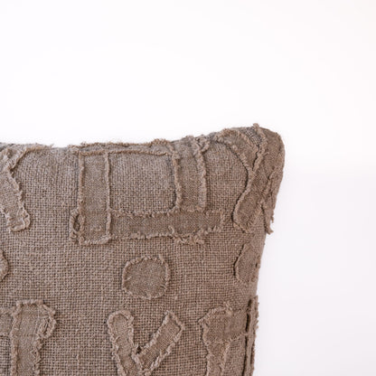 Textured brown pillow with geometric patterns on a white background