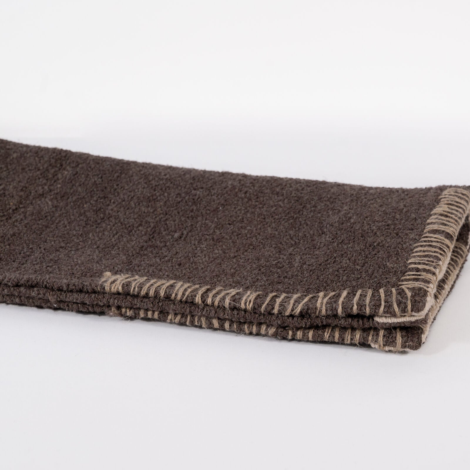 A dark brown woven bathmat on a white background