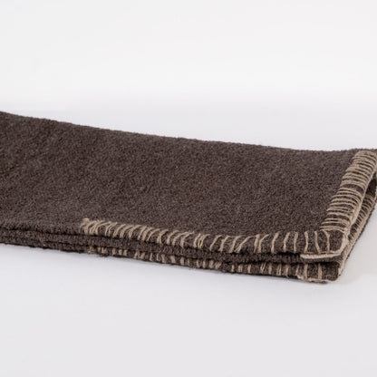 A dark brown woven bathmat on a white background