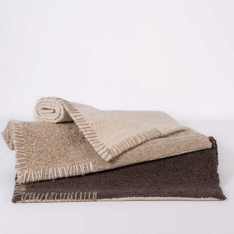 Folded beige, natural and brown bathmat on a white background