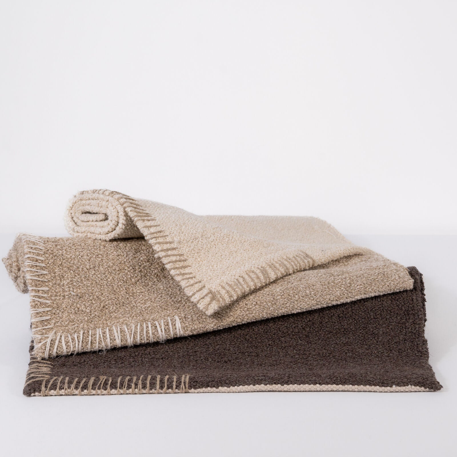 Folded beige, natural and brown bathmat on a white background