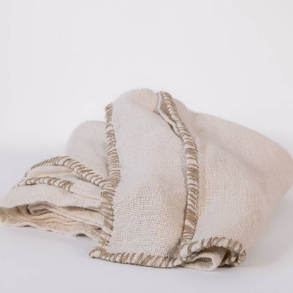 Beige woven table cloth with handstitched edges on a white background