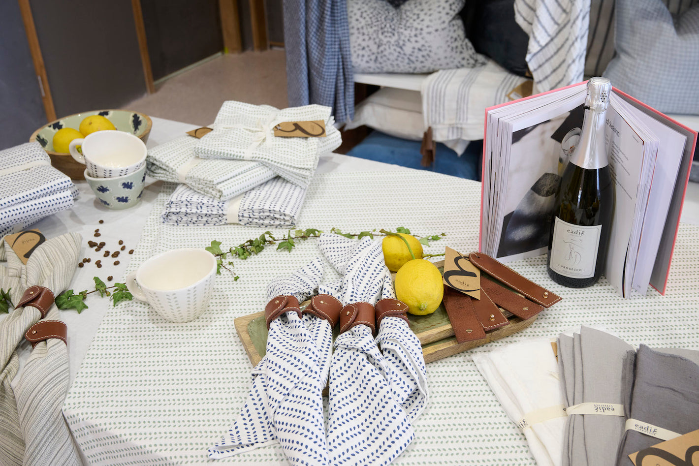 newcastle showroom on greenway street with the tableware display of napkins, tablecloths, platters, bowls and mugs in navy and sea mist accent colours.
