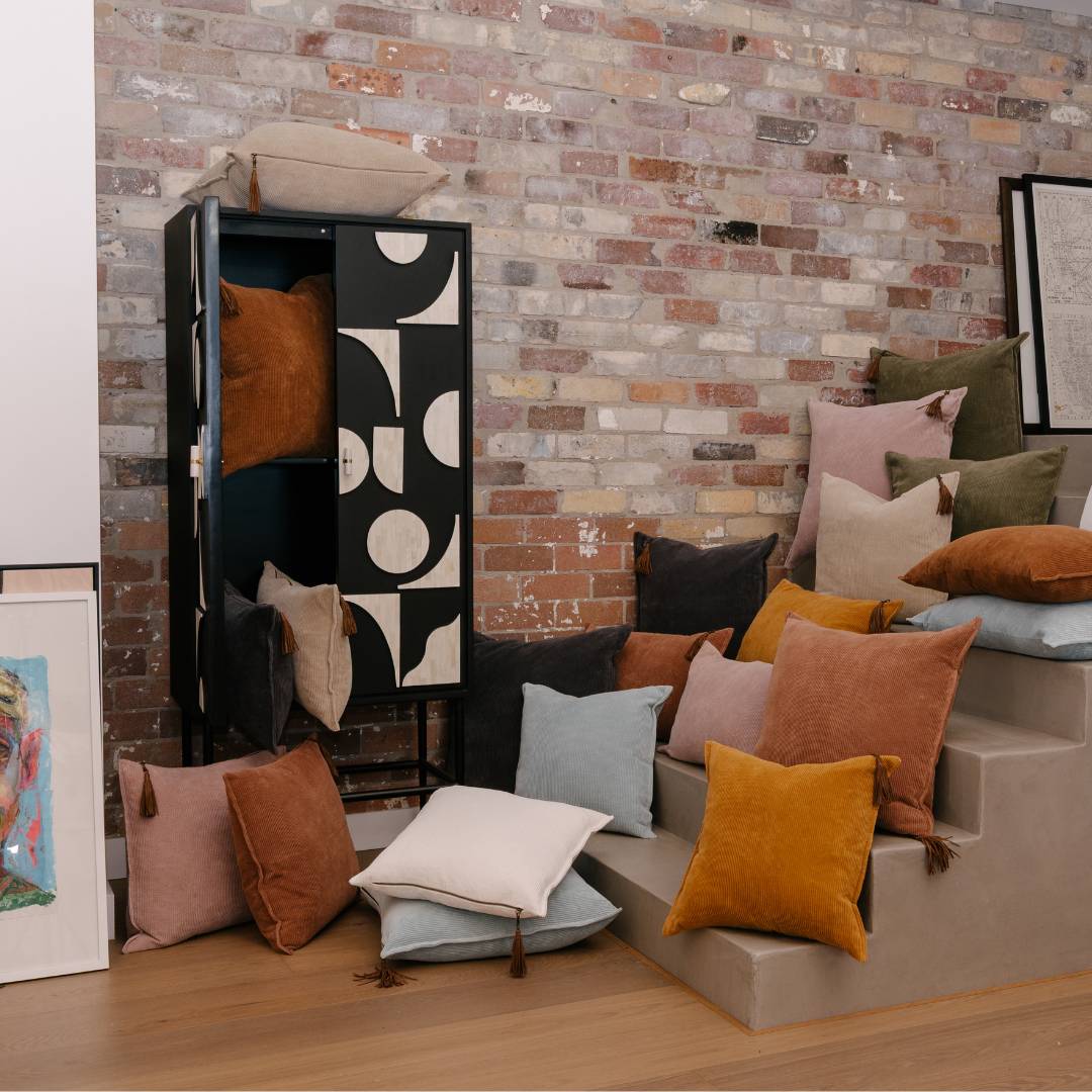 Colorful pillows on a staircase against a brick wall