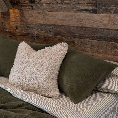 Textured pillow on a bed with dark green bedding.