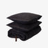 Stack of black textured pillows and a blanket on a white background