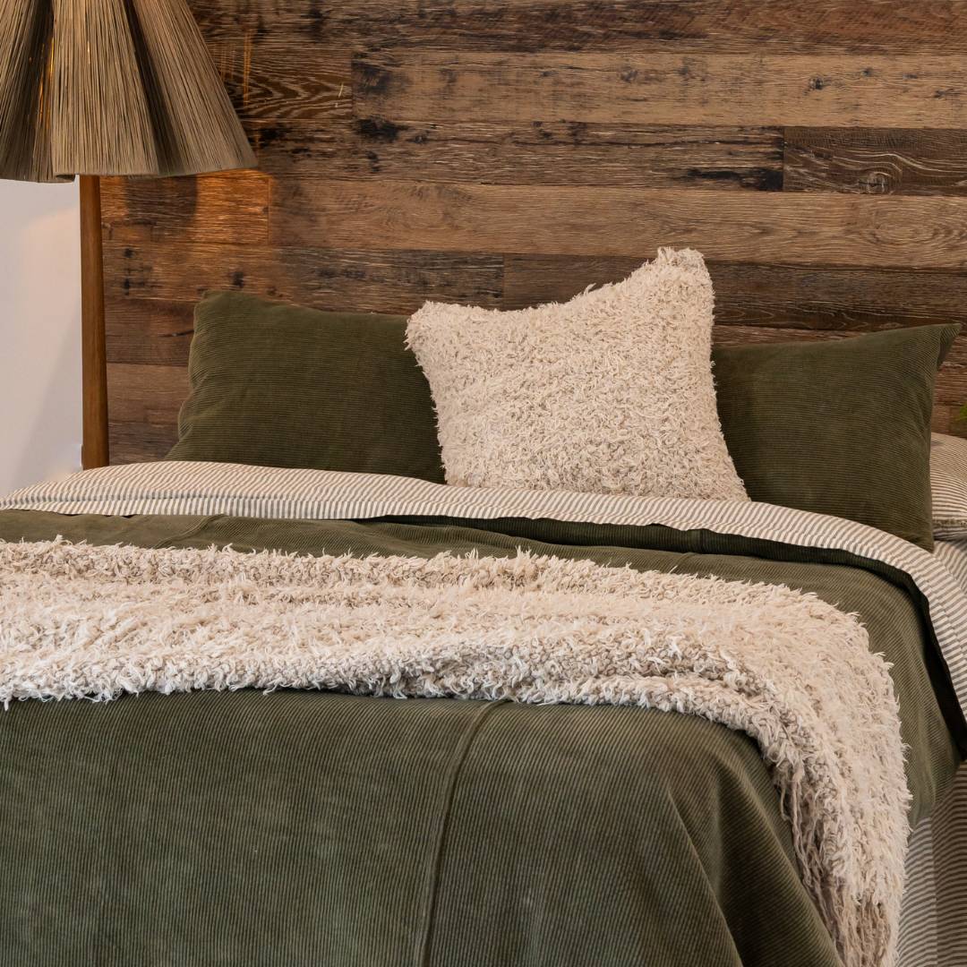 Dark green comforter on a bed in a bedroom with abstract art and decor.