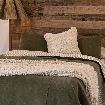 Dark green comforter on a bed in a bedroom with abstract art and decor.