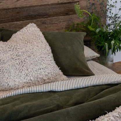 Cozy outdoor seating area with cushions and a blanket against a wooden wall.